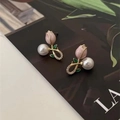 Macro detail of tulip flower earrings with pearls and green enamel leaves on a magazine - Crossed Tulip (1213)