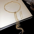 Detalle del conjunto de collar con borlas doradas y pendientes en una caja de regalo - Dorado