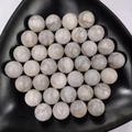 Top-down view of smooth 25mm natural white quartz crystal spheres in a black tray - 25mm No Hole Sphere / Phoenix Agate