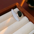 Détail d'une bague ovale argentée avec émail noir et blanc dans un écrin en lin - Blanc-Noir
