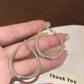 Detailansicht der silbernen minimalistischen elliptischen U-förmigen Kreolen in der Hand. - Minimalistisches Ovaler Stil(HE23106) / Durchmesser 3.3cm / Silber