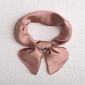 Minimalist square silk scarf in dusty rose pink tied into a bow on textured background - Lotus root pink