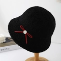 Plush black lamb wool bucket hat with a red bow and floral button on a wooden stand - Black