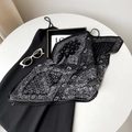 Detailed view of black and white paisley pleated scarf on a table with fashion accessories - Black (Paisley)