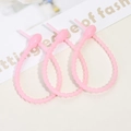 Close-up of three soft pink silicone cable ties with non-slip granular texture design - Luminous Pink