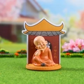 Cute smiling monk statue in orange robes sitting on a yellow base with zen background - 034-23A Peace and Quiet Set