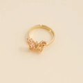 Détail d'une bague papillon dorée avec zircons roses sur un fond beige minimaliste - Ouvert Réglable / 8# Pêche