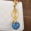 Sparkling dark blue apple keychain with vintage gold hardware on a quilted handbag - Glitter Blue