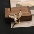 Spilla a foglia dorata con zirconi brillanti e perla su supporto di legno - Stile Foglia / Stile Spilla