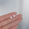 Irregular silver heart stud earrings with metallic texture held for size reference - Brushed 3D Heart / Silver