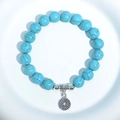 Turquoise beaded bracelet with silver spacer beads and hollow circular charm on white plate - Blue Turquoise Hollow Round Charm