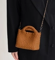 Detail view of woven brown bucket bag featuring braided leather handle and metal chain strap - Brown
