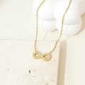 Detailed view of gold infinity necklace with cubic zirconia on white stone pedestal - Gold Full Zirconia Infinity