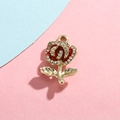 Dettaglio di un ciondolo rosa con smalto rosso, strass bianchi e base in lega dorata - Rosa Rossa Oro