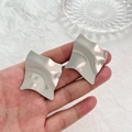 Dettaglio macro di orecchini a onde argentati irregolari con trama in metallo lucido - Orecchini Argento Stile Onda Irregolare (K-1565)