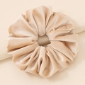 Close-up of champagne velvet scrunchie showing detailed soft pleated texture and sheen - Beige