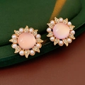 Dettaglio macro di orecchini vintage a girasole con gemma rosa e perle bianche - Stile Pietra Occhio di Gatto Rosa