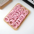 Detailed view of elastic pink hair ties neatly organized on a wooden display tray - 50 Pieces / Pink