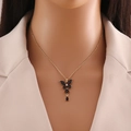 Collana dorata con ciondolo a farfalla nera e piccola gemma indossata da modella - Nero