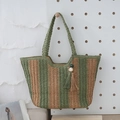 Grün und braun gestreifte Stroh-Tasche mit Perlenquaste hängend an einer Lochplatte - Grün und Braun gestreift / Grün