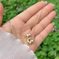 Macro detail of high-shine gold-plated 3D bubble letter E pendant necklace for women - Gold E