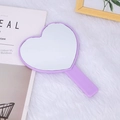 Dettaglio dello specchio a mano viola a forma di cuore su fondo di peluche bianco - Viola