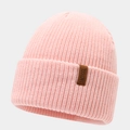 Detail of light pink ribbed knit beanie featuring a brown leather label with IACUGGL text - Pink