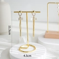 Golden long tassel earrings with white butterfly stone on a gold jewelry display stand - Metal T-Bar Rack