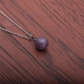 Gros plan d'un pendentif rond en pierre violette sur chaîne argentée sur bois - Violet (Améthyste)