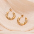Pendientes dorados en forma de C estilo bambú con brillantes sobre tela de seda beige - Oro de 18K / Dorado