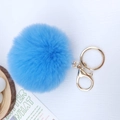 Detailed view of blue fluffy pompom keychain with golden metal clasp on white background - Lake Blue