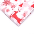 Macro detail of Christmas wrapping paper featuring red reindeer and snowflake prints - Christmas Reindeer