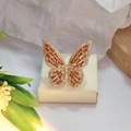 Close-up of golden hollow butterfly ring with orange stones and zircon details - Gold Color Orange Zirconia