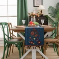 Dark blue embroidered floral table runner with tassels displayed on a wooden dining table - Blue Bottle + Red Tassel (Hand Wash Only)