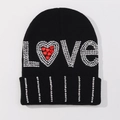 Close-up of LOVE lettering with sparkling rhinestones and a red heart on a black knit beanie - One Size / Black