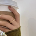 Bague spirale dorée minimaliste à double couche portée par un mannequin avec un café - Bague Torsadée Dorée