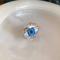 Vista macro del anillo Ojo Turco de metal líquido con iris azul y acabado plateado pulido - Plateado