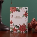 Premium Christmas card with gold foil lettering and festive pine patterns on a wooden table - Poinsettia Gold Foil