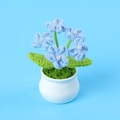 Close-up of handmade crochet blue flowers with pearl centers in a white ceramic pot - Blue Forget-Me-Not (5 Pearl Heads) Potted Plant