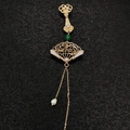 Détail d'une broche chinoise en forme d'éventail doré avec perles et glands élégants - Éventail Pliant à Motifs