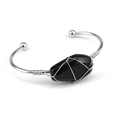 Macro detail of handmade silver wire wrapped raw black crystal stone on an open bangle - Obsidian