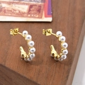 Elegant gold C-shaped hoop earrings featuring inlaid white pearls on a wooden surface - C-Shape Row Pearl