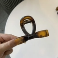 Detailed macro view of a tortoiseshell resin hair claw clip with a ribbon bow shape - Medium 8cm / Glossy Light Tortoise
