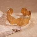 Dettaglio del bracciale rigido dorato con trama circolare su base in pietra naturale - Piccolo / Polsino a onde aperte / Oro