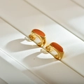Dettaglio macro di orecchini geometrici placcati oro con smalto arancione vivace - Arancione