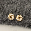 Detailed close-up of French vintage gold knot earrings with white enamel on grey wool - White Concentric Knot - Gold Plated