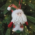 Santa Claus plush ornament with red and green plaid fabric hanging on a Christmas tree - Red Hat Santa