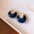 Detailed macro of C-shaped blue marble resin earrings with gold plating on a ceramic tray - Ear Buckle - Blue Marble Texture