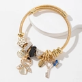 Golden mesh charm bracelet with angel, star and heart key pendants on white pedestal - White