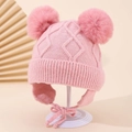 Detail der Baby-Strickmütze mit rosa Bommeln und weichem Zopfmuster auf Display - 1-3 Jahre / Rosa